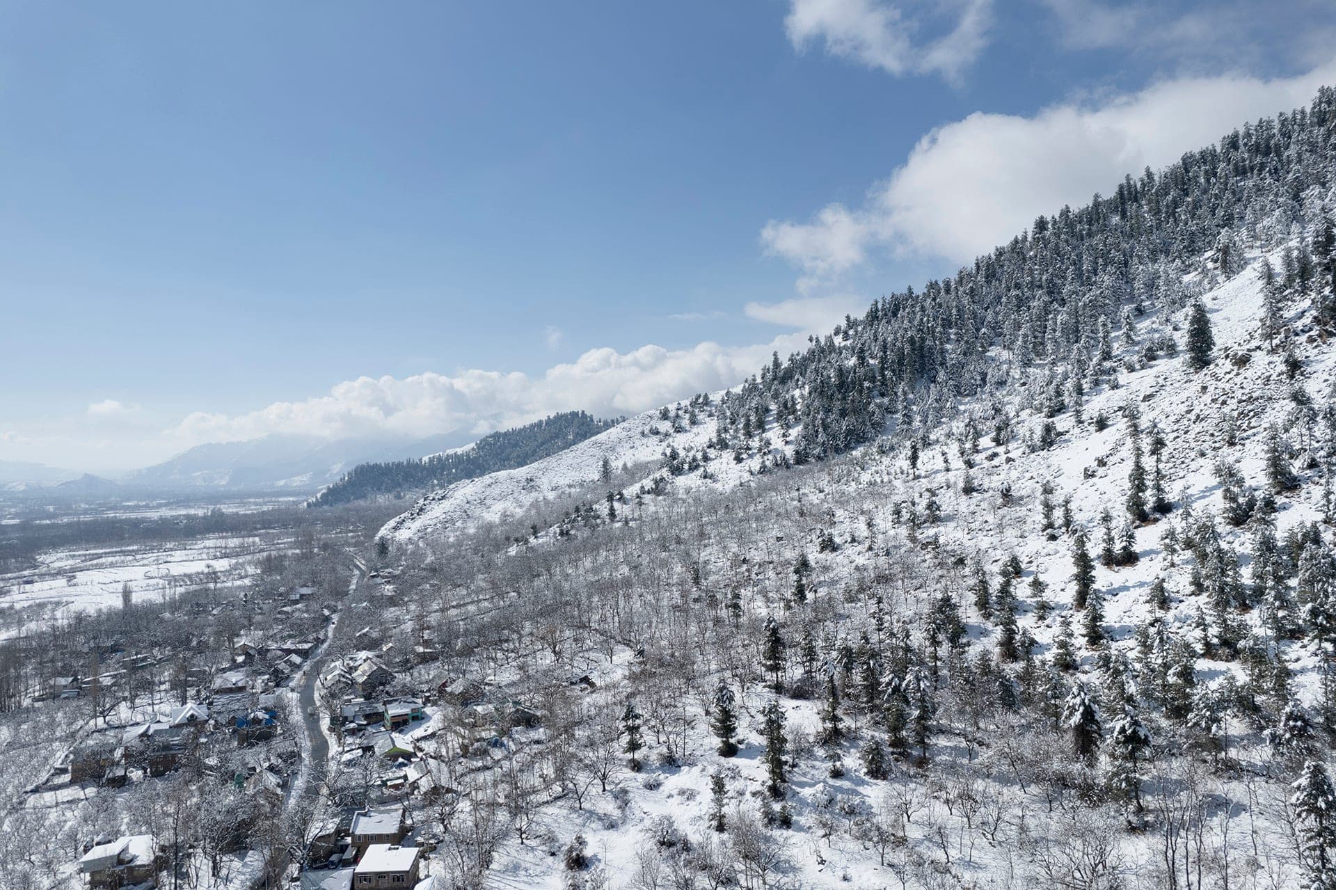 Snow-covered mountain slope and village near Pahalgam