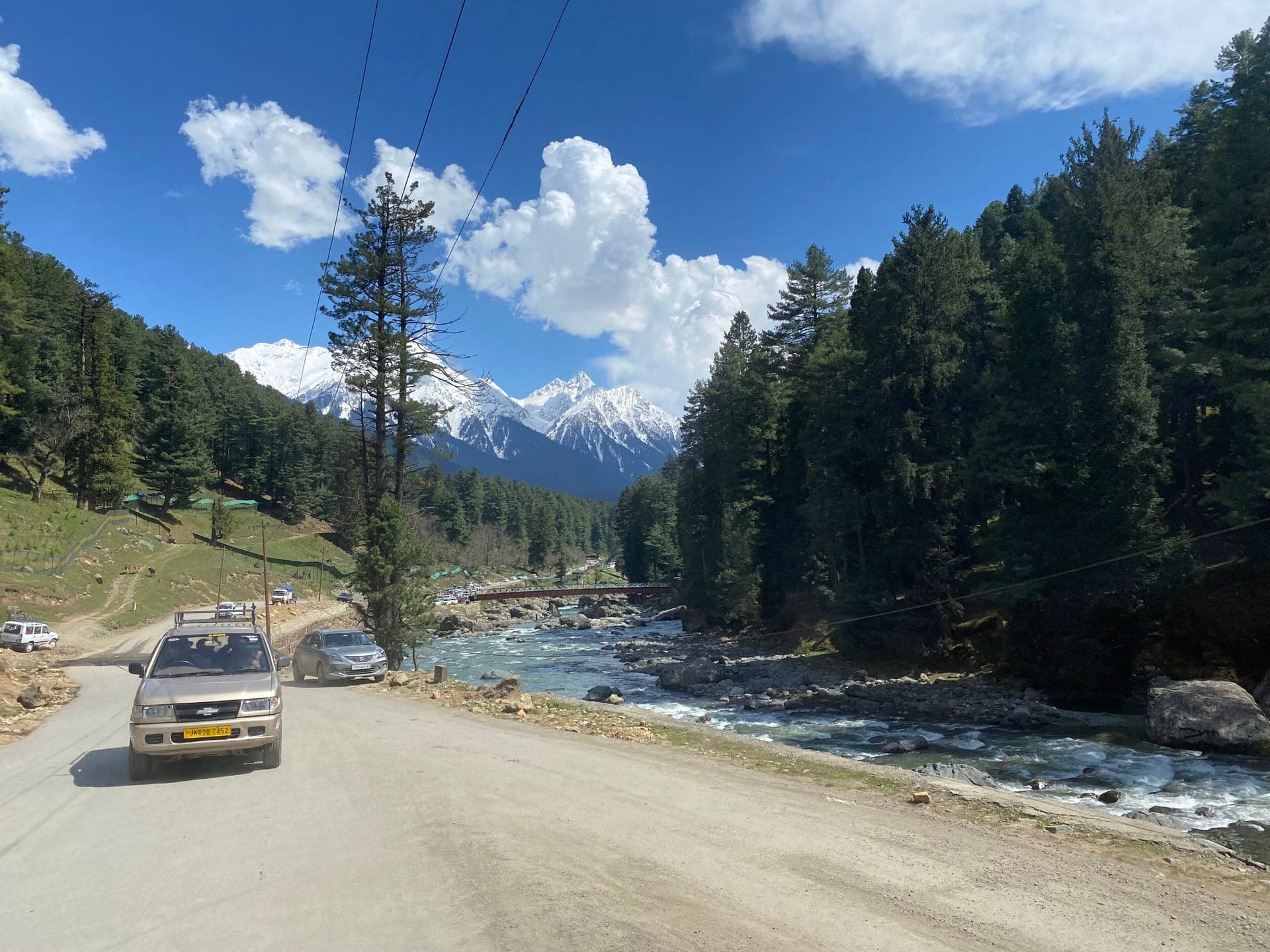 Taxi on the road to Pahalgam beside the Lidder River, with pine forest and snow-capped peaks ahead