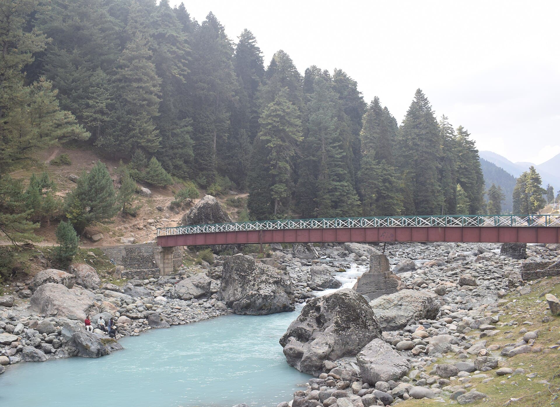 A footbridge over the turquoise Lidder River below pine forest in Pahalgam A footbridge over the turquoise Lidder River below pine forest in Pahalgam